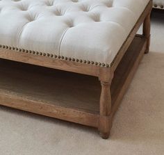 a white ottoman sitting on top of a carpeted floor next to a wooden shelf