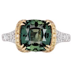 This ring is a stunning piece that combines elegance with uniqueness. The 4.50 carat cushion-cut Green Sapphire at the center is not only impressive in size but also comes with a GIA certification, ensuring its quality and authenticity. The green hue adds a rare and captivating touch. The center green sapphire is flanked by 0.24 carats round yellow diamonds and set in yellow gold. An additional 0.36 carats white diamonds decorate the side shank. All these combine to create a visually striking an Green Montana, Brilliant Cut Diamond Ring, Green Sapphire Ring, Yellow Diamonds, Buying An Engagement Ring, Diamond Fashion Rings, Fine Diamond Jewelry, Sapphire And Diamond Ring, Vintage Style Rings