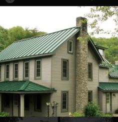 a house with a green roof and trees in the background