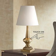 a lamp on a table next to a chair with a sign that says touch on