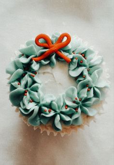 a cupcake decorated with blue frosting and an orange bow