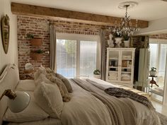 a bedroom with brick walls, white bedding and a chandelier hanging from the ceiling