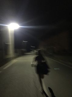 a person riding a skateboard down a street at night with the lights turned on