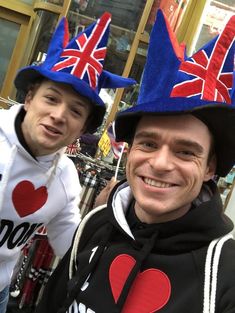 two men wearing hats with the british flag on them, one is smiling at the camera