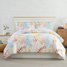 a bed in a room with a white brick wall behind it and a plant pattern on the comforter