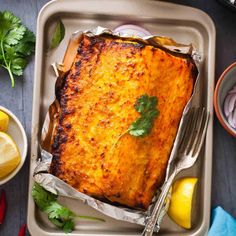 a pan with some food on top of it next to lemons and other foods