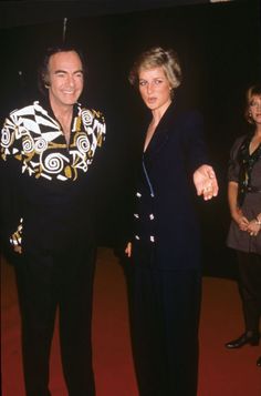 two people standing next to each other on a red carpet