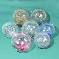 several different colored glass balls on a blue surface with white and pink speckles