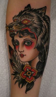 a woman's arm with a wolf head and feathers tattoo on the left leg