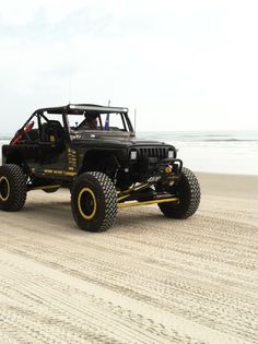 a black jeep driving down a sandy beach