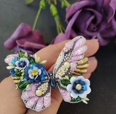 a close up of a person's hand holding two flower shaped brooches