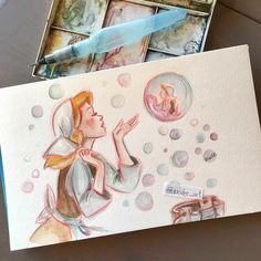 a drawing of a girl blowing bubbles with her hand on top of the box, next to some cards and a pen