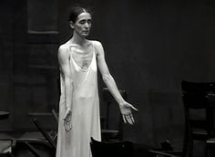 a woman in a white dress standing next to a piano