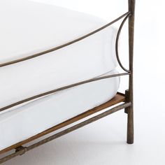 an iron bed frame with white sheets and pillows on the bottom, against a white background