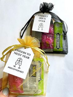 two bags with wine labels on them are being held by someone's hand