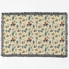 a blanket with an image of people riding horses and cactuses on the ground,