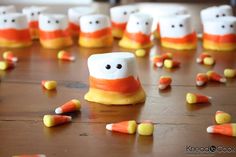 marshmallows and candy corn arranged in the shape of ghost faces on a table