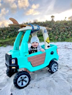 a small child in a toy car on the beach