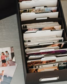 an open file cabinet filled with files on top of a table next to a photo