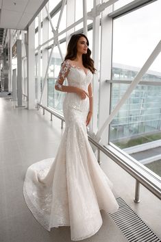 a woman in a white wedding dress posing for the camera with her hands on her hips