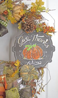 a sign that says give thanks to the pumpkins and leaves on the front door