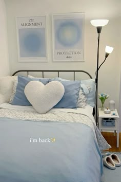 a bed with blue sheets and pillows in a bedroom next to two pictures on the wall