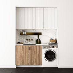 a washer and dryer in a white kitchen with wooden cabinets, marble counter tops