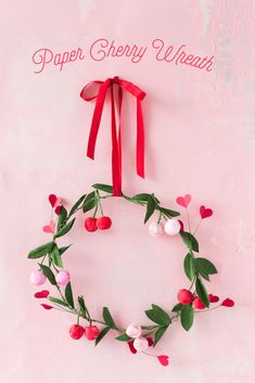 a paper cherry wreath hanging on a wall with red ribbon and flowers in the center