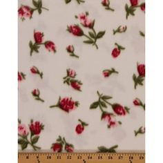 a white and red rose print fabric with green leaves on the bottom, in front of a ruler