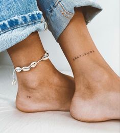 two people with tattoos on their feet and one is wearing a chain ankle bracelets