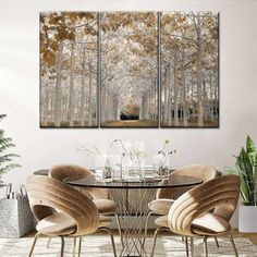 a dining room table with four chairs and three paintings on the wall in front of it