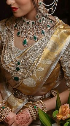 a woman in a gold and green outfit with jewelry on her head, sitting down