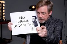 a man holding up a sign with the words may laforge be with you