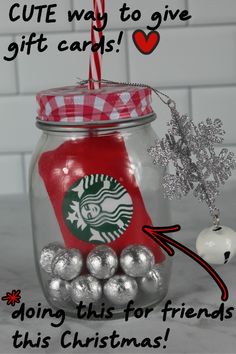 a glass jar filled with silver balls and a red starbucks mug ornament next to it