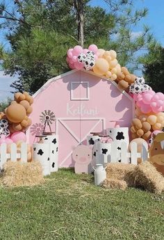 a pink barn decorated with balloons and farm animals