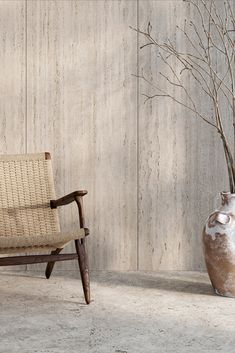 a chair and vase sitting next to each other on the floor in front of a wall