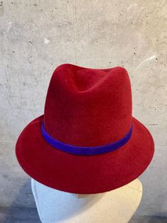 A hand made Men's hat form with a short brim, which looks great on men and women. In the pictures you can see a beautiful cherry red, rabbit hair felt hat, featuring an ultraviolet hand made felt band. We do not use any stiffeners to ensure the hairs are soft to touch. With proper care the hat can last for a very long time. We are happy to customise your order. You can customise the colour of the hat and the felt band it comes with. You can also request a grosgrain band instead of the felt band (which reduces the price by €21). The hat can be made in almost any size you need. All our hats are hand made in the centre of Berlin or Frankfurt by us. If you are in the area you can come and pick up your order in person from our stores. The hats are posted in a protective cardboard hat box. Cardboard Hat, Trilby Fedora, Hat Form, Red Rabbit, Hat Box, Felt Hat, Cherry Red, Ultra Violet, Fedora