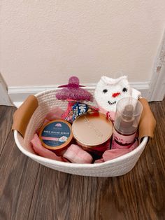 a white basket filled with baby items on top of a wooden floor