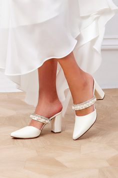 "Taking a simple shape and adding some elegant sparkle, the Dorothea bridal mules with block heel are a stylish new pair of our wedding shoes collection. Handcrafted with care from high-quality leather, they have pointed toes and are embellished with crystals and pearls along the arch strap. A contemporary take on a classic shape, these backless shoes are the epitome of chic.  They come in 3 colors and in 2 heels height: 8 cm (3\") and 5 cm (2\"). Our mules for wedding run true to size. Please order your usual dress shoe size.  If you wear half size or you are between two sizes go DOWN to the nearest whole size. We also offer custom width (wide or narrow) upon request pre-order. * Ethically handmade upon order by skillful artisans in Athens, Greece * Lamb leather upper and lining * Lamb le Pearl White Ankle Strap Heels For Formal Occasions, Pearl Embellished High Heels For Bridal Shower, Pearl Embellished Heels For Bridal Shower, Pearl Embellished Wedding Shoes For Prom, Pearl White Wedding Shoes For Bridal Shower, Pearl White Ankle Strap Wedding Shoes, Round Toe Heels With Rhinestones For Wedding, Wedding Heels With Rhinestones And Round Toe, Pearl White Bridal Accessories For Party