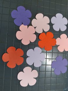 several different colored paper flowers on a tile floor