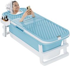 a woman laying in a bath tub with a cell phone next to her and bottles on the side