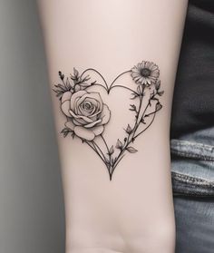 a heart shaped tattoo with flowers and leaves on the side of the leg, in black ink