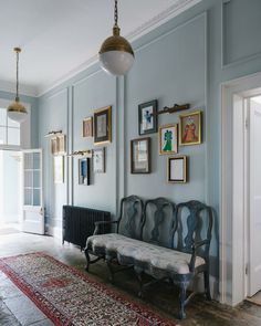 an ornate bench sits in the middle of a room with framed pictures on the wall