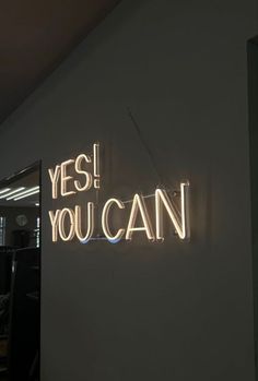 a neon sign that says yes you can on the side of a wall in an office