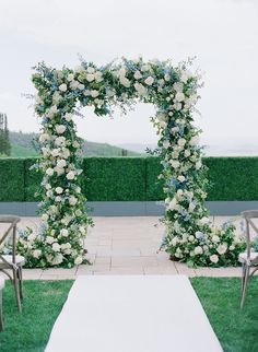 an outdoor ceremony setup with white flowers and greenery