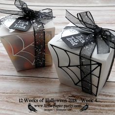 two halloween gifts wrapped in black and white paper with spider webs on the top