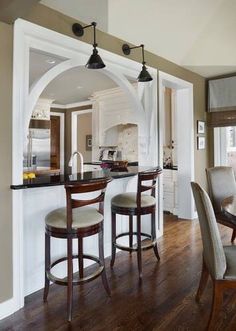 an open kitchen and dining room area with bar stools