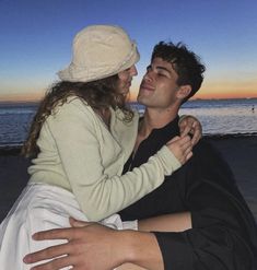 a man and woman hugging on the beach at sunset