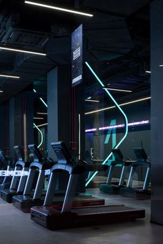 a row of treadmills in a gym with neon lights