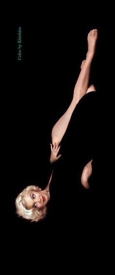 a woman laying on her back in the dark with her legs spread out and hands behind her head